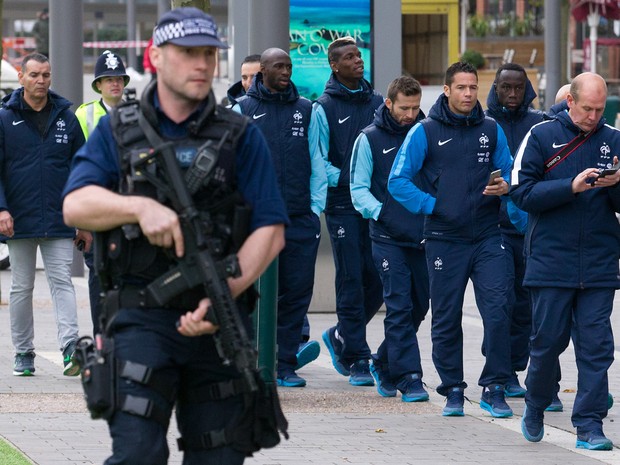 Jogadores e membros da comissão técnica da seleção da França passam escoltados por policiais armados perto do estádio de Wembley, em Londres, antes do amistoso entre Inglaterra e França (Foto: Justin Tallis/AFP)