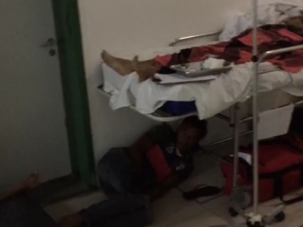Acompanhante de paciente dorme no chão, sob uma maca, no Hospital Geral de Fortaleza (Foto: TV Verdes Mares/Reprodução)