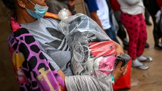 Mulher carrega uma sacola plástica com seus pertences enquanto imigrantes esperam por vaga em abrigo em San Antonio, Texas. No começo da semana, cerca de 50 imigrantes foram encontrados mortos em um caminhão abandonado perto da cidade texana  — Foto: CHANDAN KHANNA / AFP