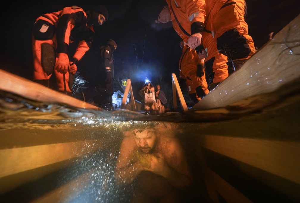 18 de janeiro - Equipes de resgate observam um ortodoxo russo mergulhar na gua gelada durante uma tradicional celebrao religiosa em So Petersburgo, Rssia — Foto: Dmitri Lovetsky/AP