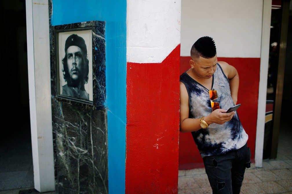 Jovem verifica celular em Cuba perto de um hotspot de internet  — Foto: Tomas Bravo/Reuters