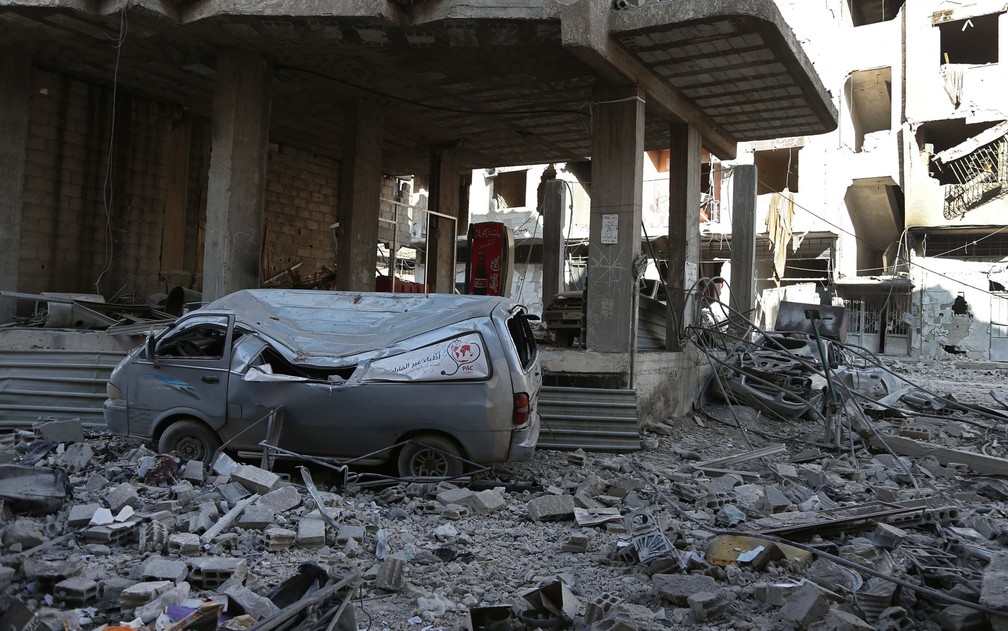 Prédio de hospital e ambulância ficam destruídos após ataque aéreo de forças do governo sírio na região da Guta Oriental, reduto de rebeldes perto de Damasco (Foto: Abdulmonam Eassa/AFP)