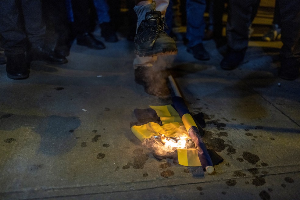 Bandeira sueca queima ao lado do Alcorão em Estocolmo, na Suécia — Foto: Umit Bektas/REUTERS