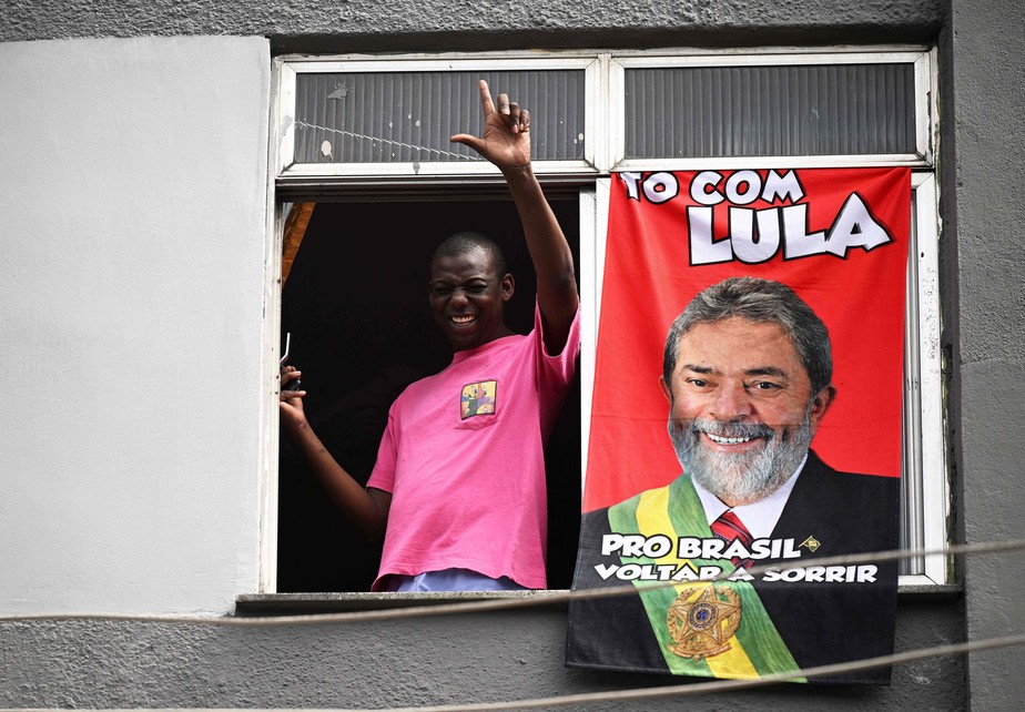 Apoiador de Lula faz gesto com a letra 'L' em janela próximo à quadra da Portela, no Rio de Janeiro