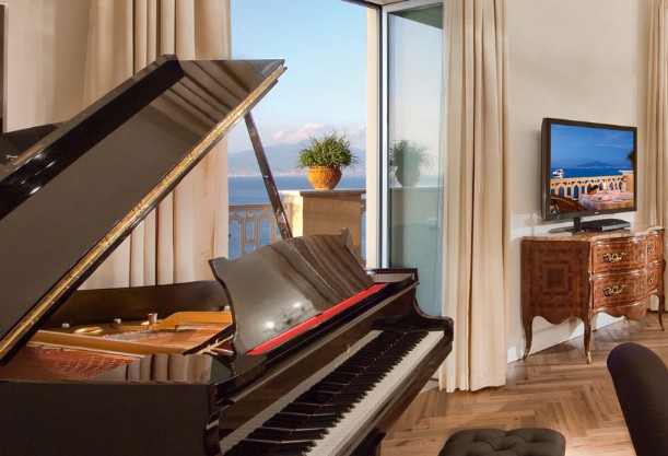 Um dos quartos do hotel com piano e vista para o mar — Foto: Reprodução/Excelsior Vittoria