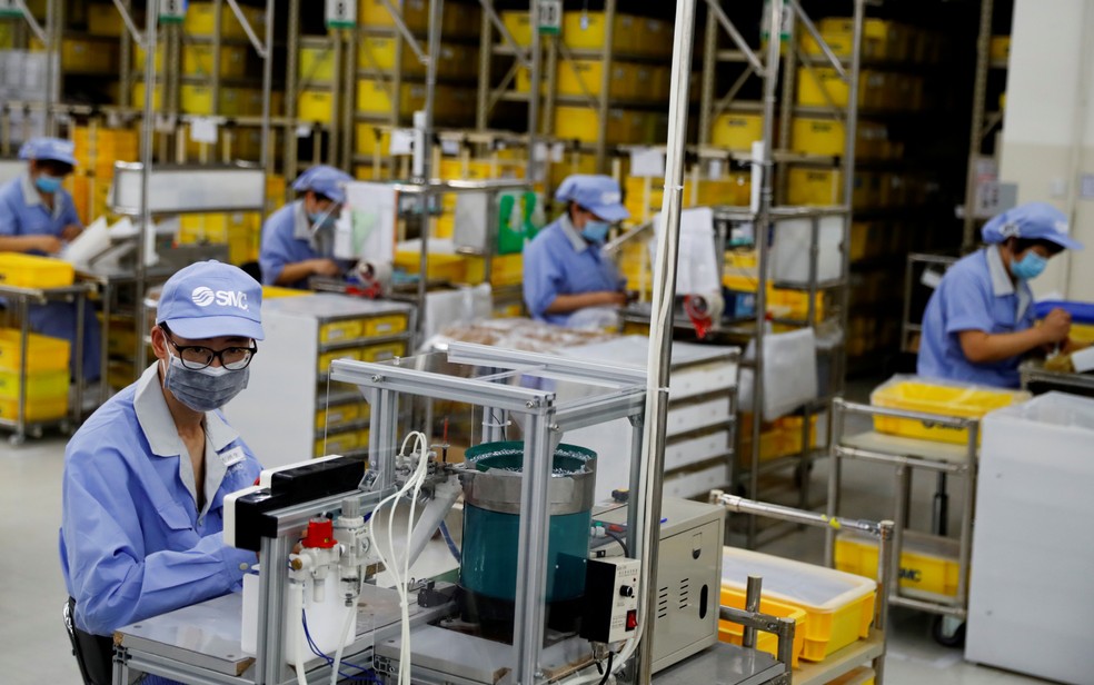 Funcionários usando máscaras trabalham em uma fábrica de componentes em Pequim — Foto: Thomas Peter/Reuters