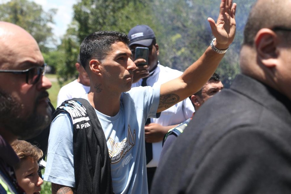 Suárez abana para a torcida do Grêmio presente no aeroporto — Foto: Gabriel Girardon/ge.globo