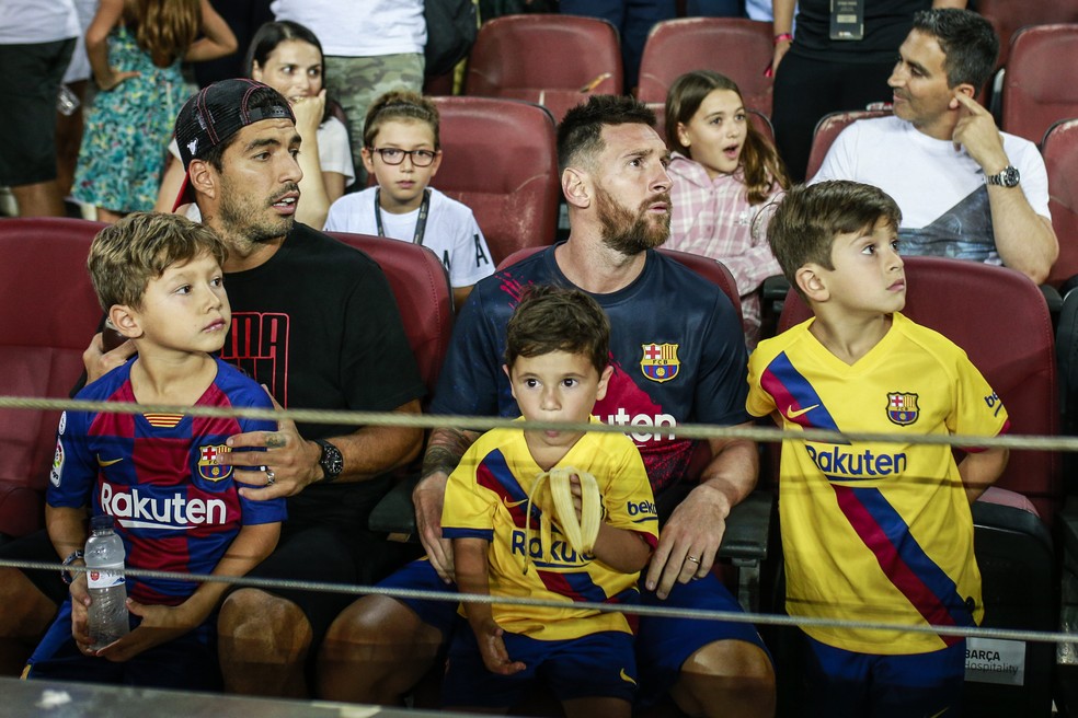 Luis Suárez com o filho Benjamin e Messi com Thiago e Mateo, durante jogo do Barça — Foto: Getty Images