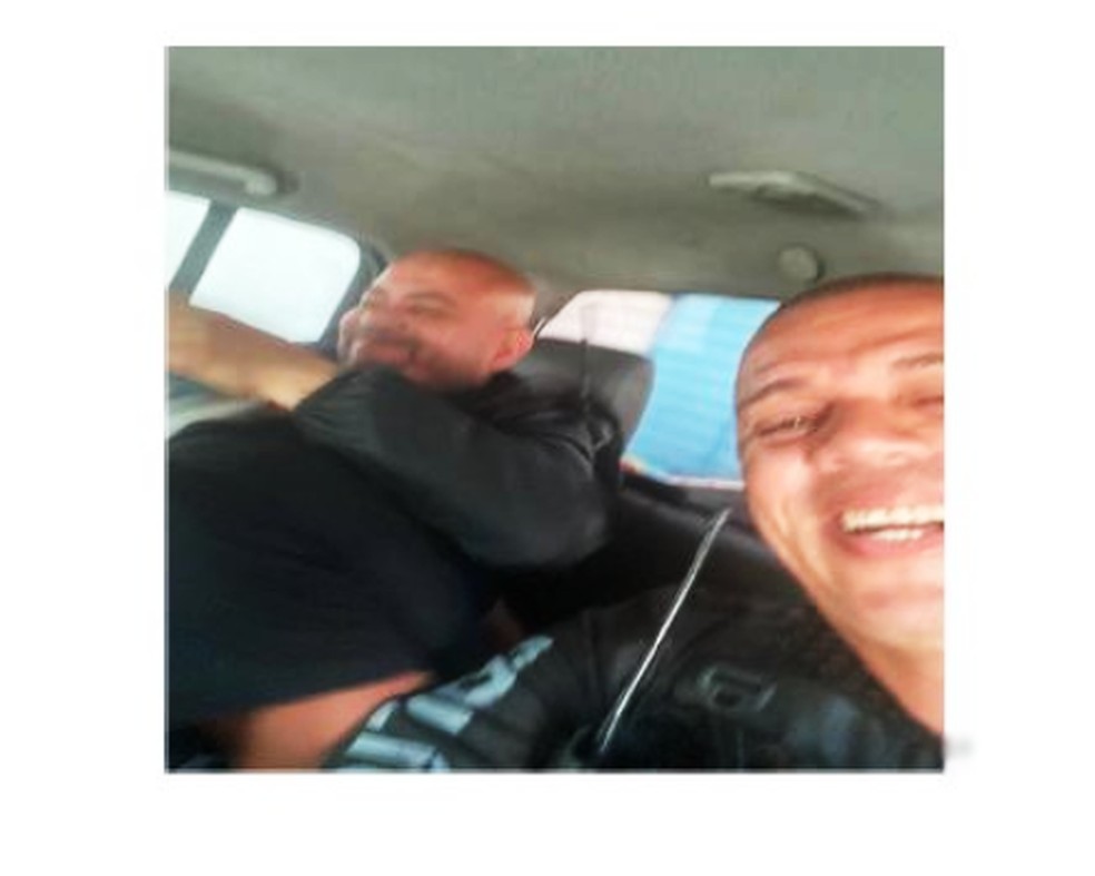 Integrantes do grupo intitulado 'Mercenários' riem enquanto trocam foto no grupo de Whatsapp torturando um traficante com saco de lixo na cabeça — Foto: Reprodução