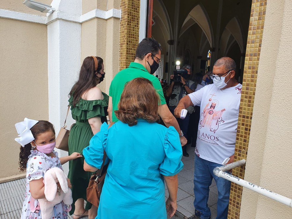 Famílias têm temperatura aferida antes de entrar na Igreja Cristo Rei, em Fortaleza — Foto: Kilvia Muniz/SVM