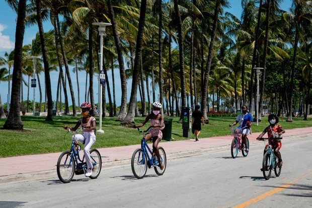 People weraing facemasks ride bicycles on Ocean Drive in Miami Beach, Florida on June 16, 2020. - Florida is reporting record daily totals of new coronavirus cases, but you'd never know it looking at the Sunshine State's increasingly busy beaches and hote (Foto: AFP via Getty Images)