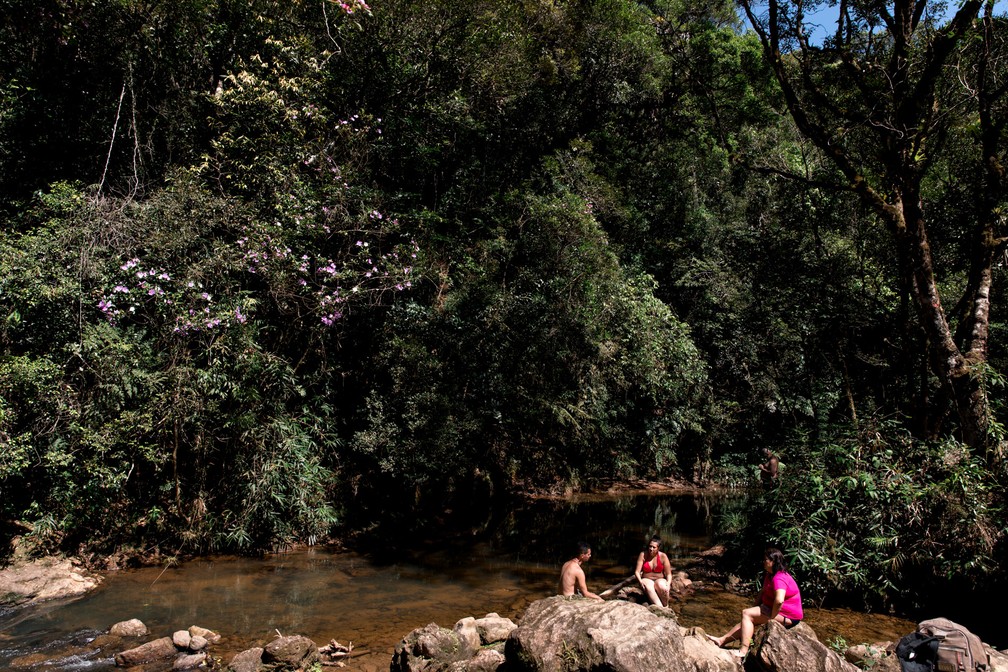 Grupo de amigos descansa na Cachoeira Poço das Virgens, com águas do Rio Monos. Acesso ao local é gratuito, após trilha suave em meio à Mata Atlântica (Foto: Marcelo Brandt/G1)