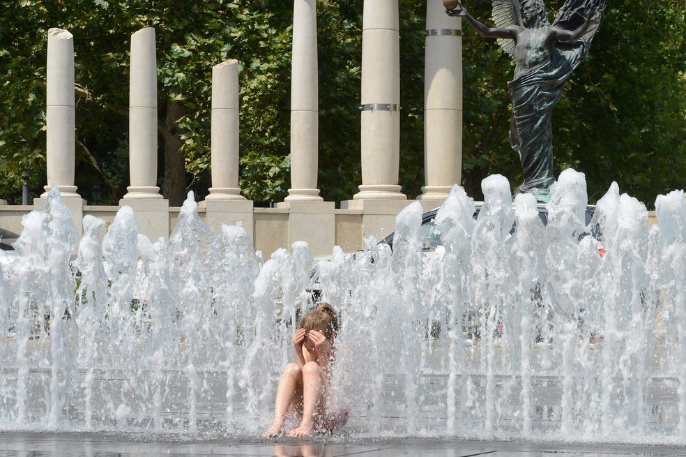 Menina se refresta em fonte de Budaeste, na Hungria, nesta quarta-feira (28); mudanças climáticas tiveram papel em onda de extremo calor na Europa no mês de junho  (Foto: Lajos Soos/MTI via AP)