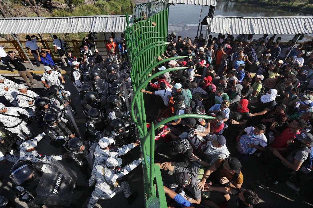 Migrantes forçam passagem pela fronteira entre México e Guatemala neste sábado (18). Policiais mexicanos fecharam o posto após determinação das autoridades locais — Foto: Marco Ugarte/AP Photo
