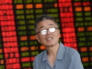 Um investidor de ações olha para cima em uma corretora de Xangai, na China. O país cortou a taxa de juros pela 4ª vez para impulsionar a economia que deve ter o pior crescimento em 25 anos (Foto: Chinatopix/via AP)