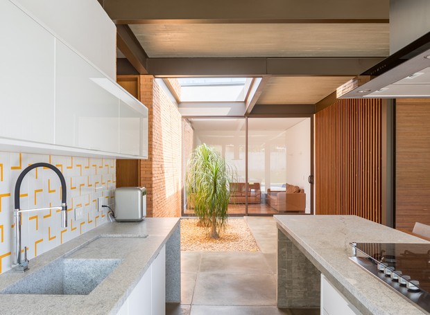 Elementos de madeira, concreto, aço e vidro deixam a casa com um estilo contemporâneo. Ao fundo, o jardim de inverno e a sala de TV  (Foto: Haruo Mikami)