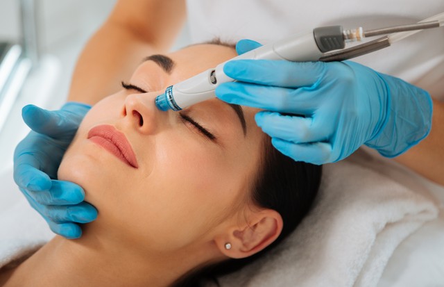 Facial procedure. Delighted nice woman lying on the medical bed with her eyes closed while having hydrafacial (Foto: Getty Images/iStockphoto)