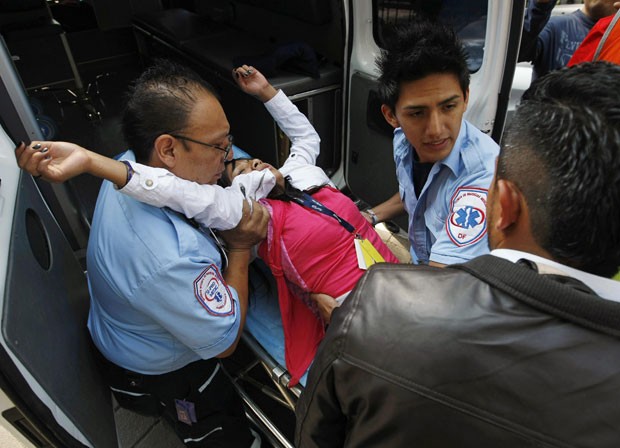 Paramédicos ajudam uma mulher que desmaiou durante retirada de trabalhadores de um prédio na Cidade do México (Foto: Bernardo Montoya/Reuters)