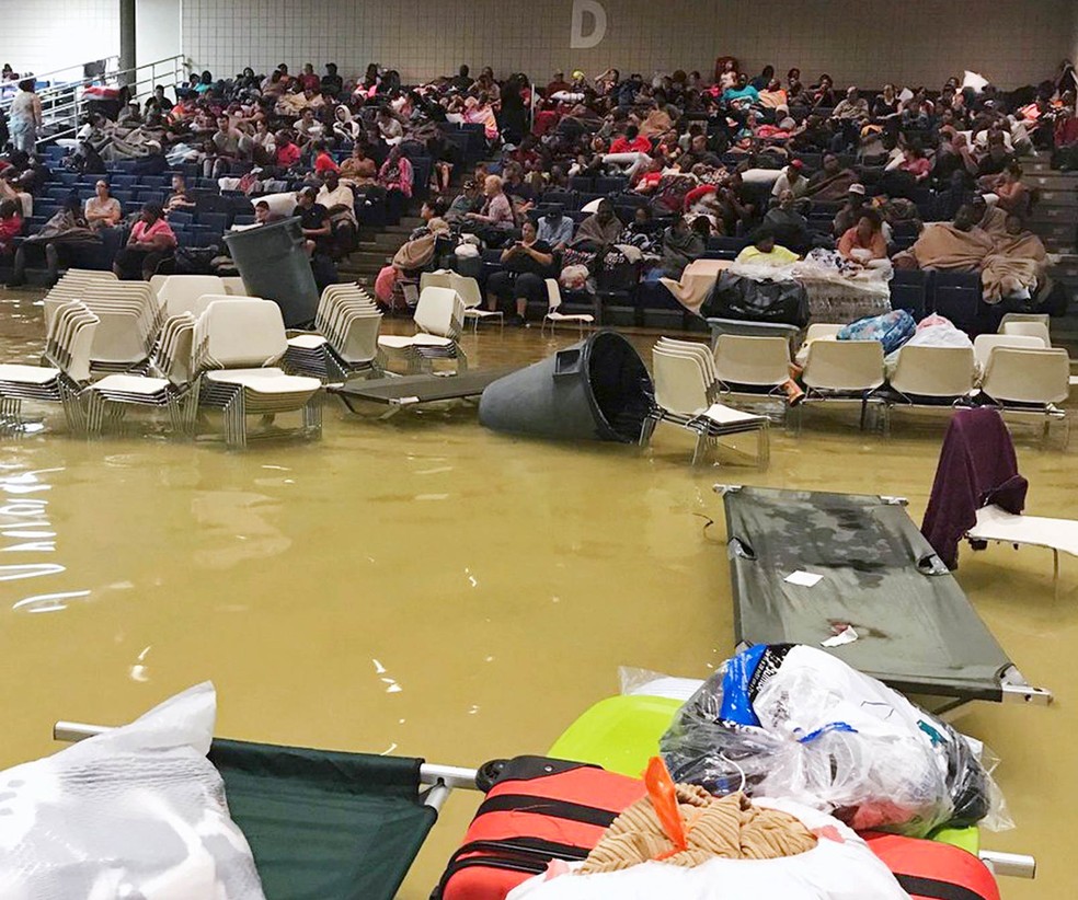 Pessoas desabrigadas ocupam área da plateia de um salão alagado no Centro Cívico Bowers em Port Arthur, no Texas, após a tempestade tropical Harvey causar o alagamento. Ainda não está claro para onde as famílias serão transferidas (Foto: Beulah Johnson via AP)