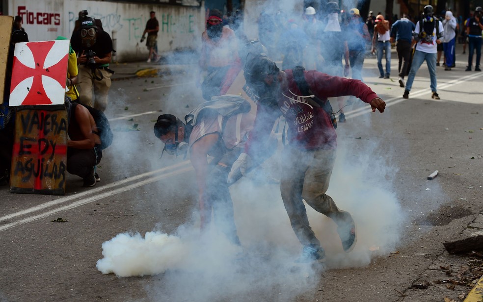 Manifestantes se preparam para atirar de volta bombas de gA?s em policiais durante protesto contra o governo em Caracas, na Venezuela, na quinta-feira (20) (Foto: Ronaldo Schemidt/AFP)