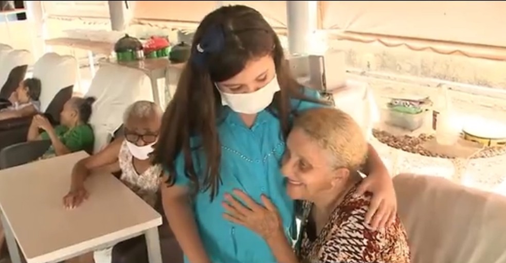 Maria Clara, estudante de Cajazeiras, lê livros para os idosos e serve lanche preparados por ela durante as visitas. — Foto: Reprodução/TV Cabo Branco