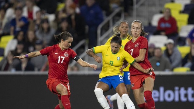 Debinha disputa a bola entre duas jogadoras do Canadá na derrota da seleção brasileira