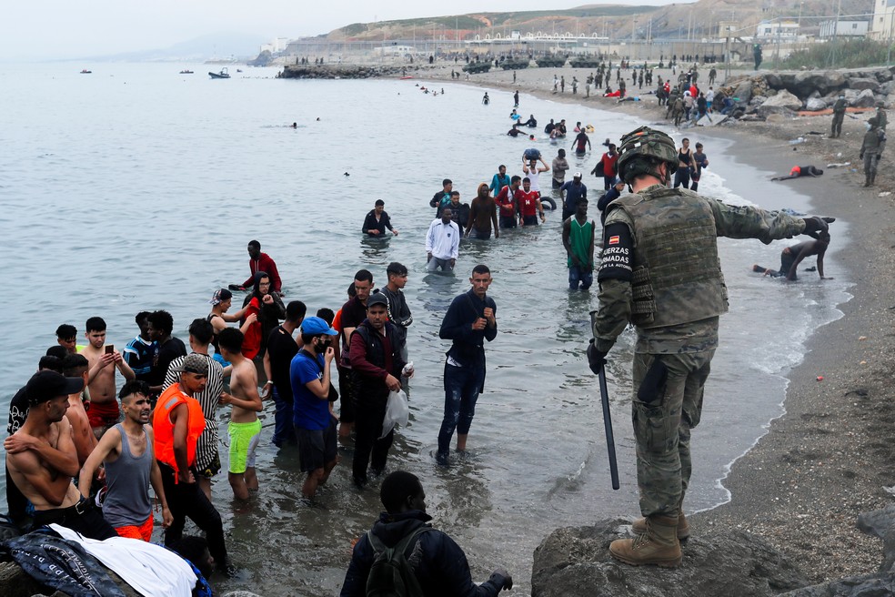 Soldado espanhol dá ordens a imigrantes que nadaram até o território de Ceuta, enclave da Espanha no Marrocos — Foto: Jon Nazca/Reuters
