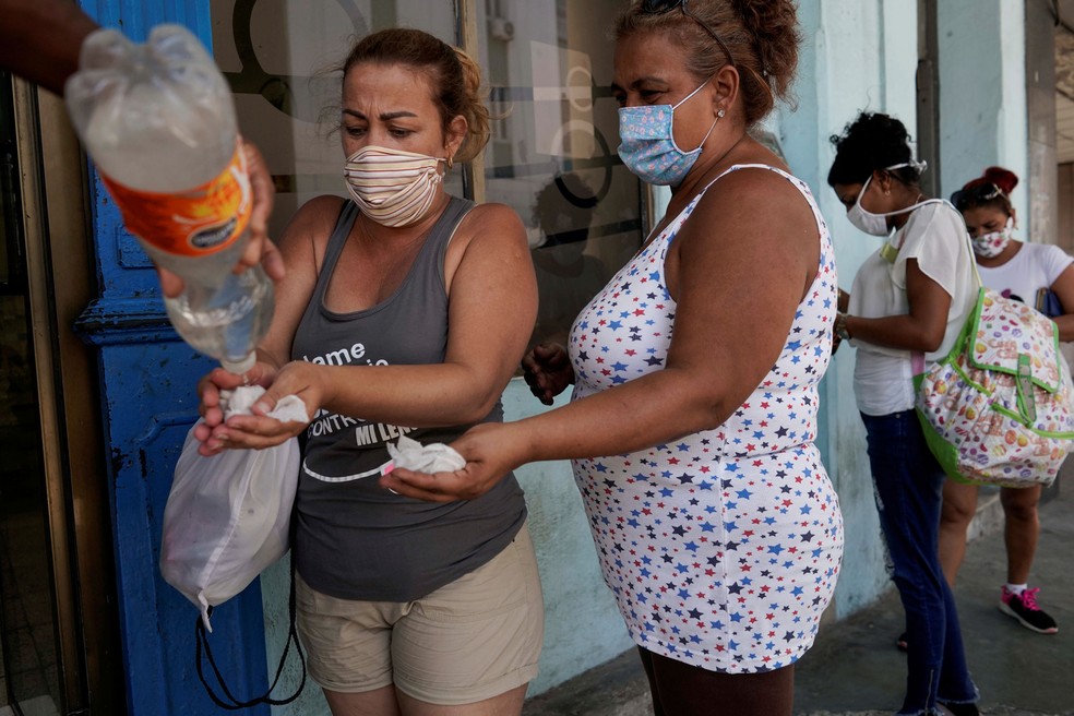 Cubanas dividem produto para higienizar as mãos em Havana, Cuba. Imagem de 8 de julho  — Foto: Alexandre Meneghini/ Reuters