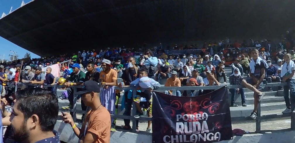 Migrantes ocupam arquibancada de abrigo improvisado na Cidade do México para assistir a apresentação de luta livre — Foto: TV Globo/Reprodução