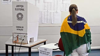Mulher enrolada em uma bandeira do Brasil vota em Brasília. — Foto: EVARISTO SÁ / AFP