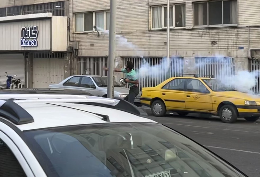 Protestante devolve bomba de gás lacrimogênio durante protesto em Teerã — Foto: Associated Press