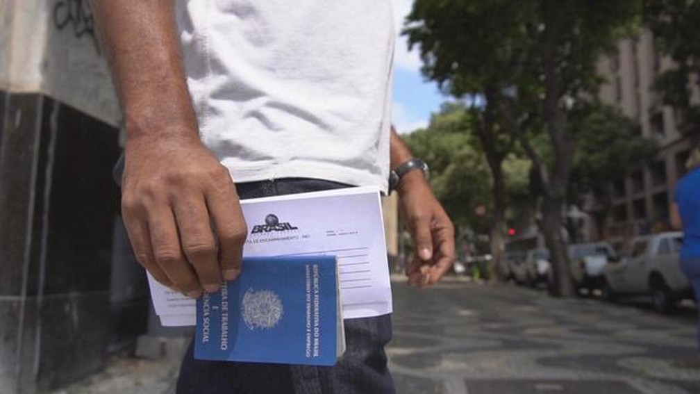 Homem segura carteira de trabalho ao deixar prédio do Sistema Nacional de Emprego (Sine) no Rio de Janeiro — Foto: Reprodução/TV Globo