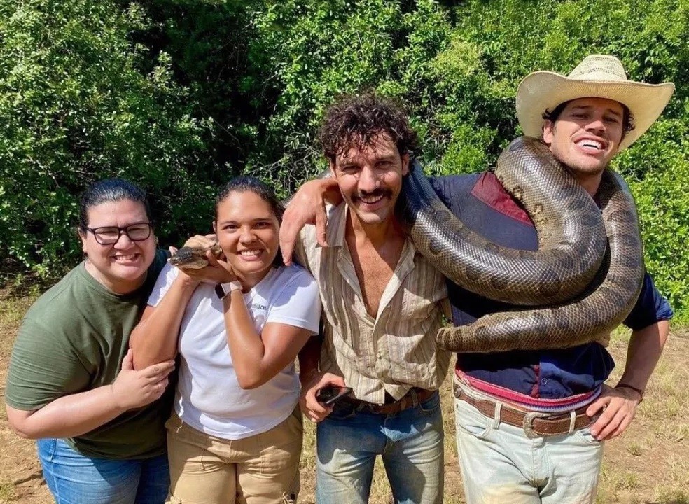 Ao lado da equipe de arte da novela os atores Guito e José Loreto carregam a réplica de sucuri nos bastidores de Pantanal (Foto: Reprodução/Instagram)