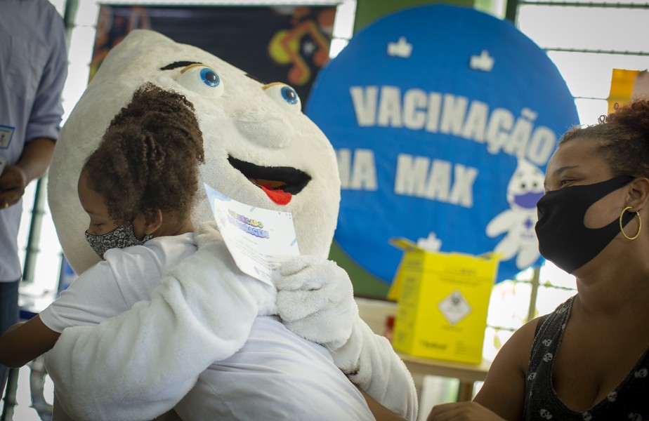 Menina abraça o Zé Gotinha após ser vacinada, no Rio.