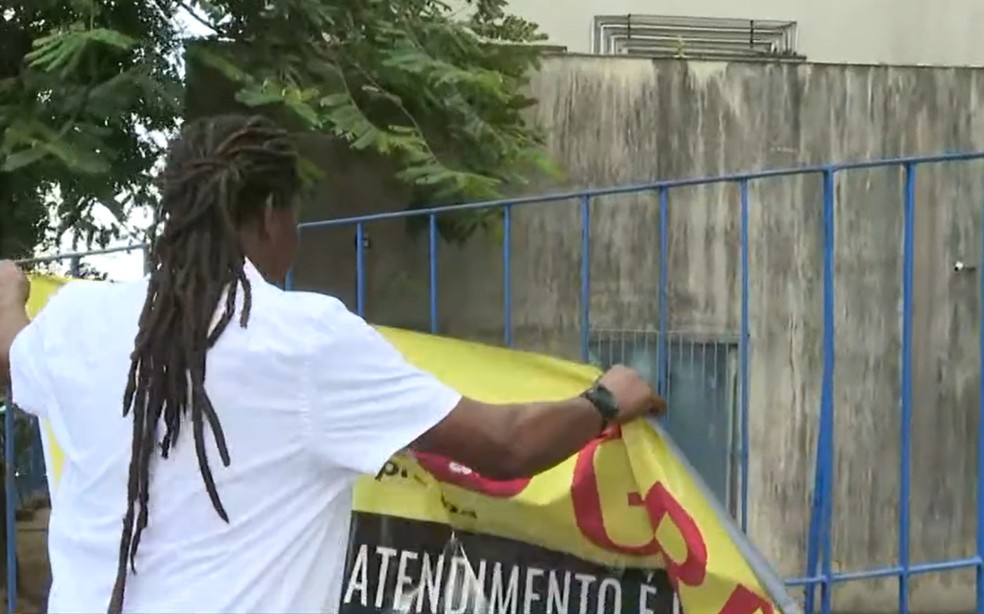 Representante dos trabalhadores retira faixa que indicava greve, no posto do INSS no bairro de Brotas, em Salvador  Foto: Reproduo/TV Bahia
