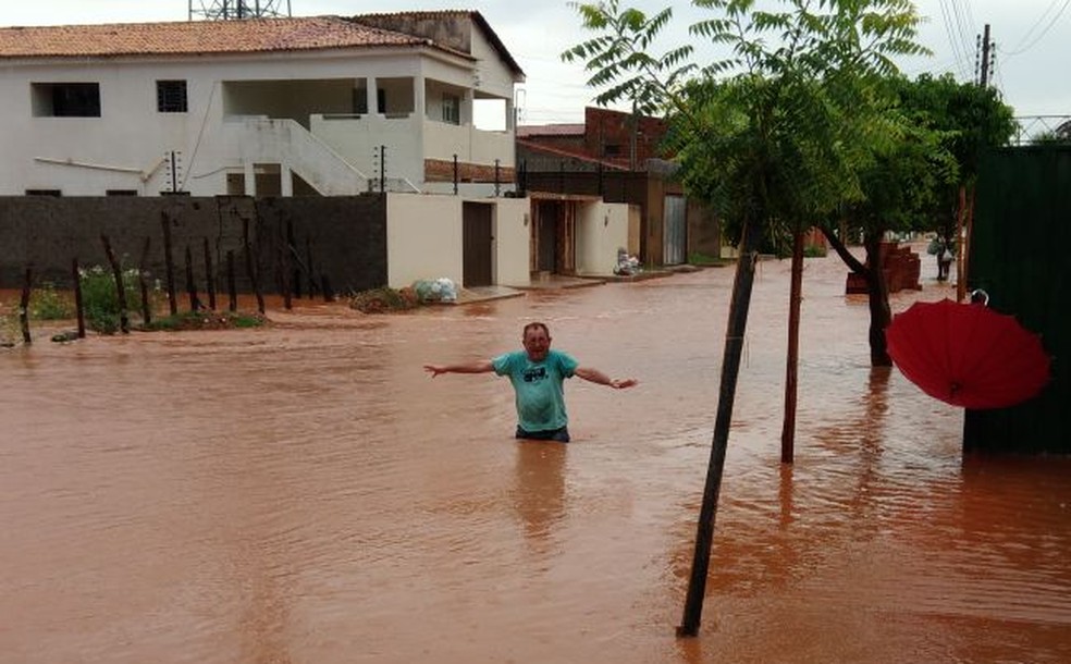 Homem tenta atravessar a rua submersa pela água  (Foto: Lázaro Parente/ Arquivo pessoal)
