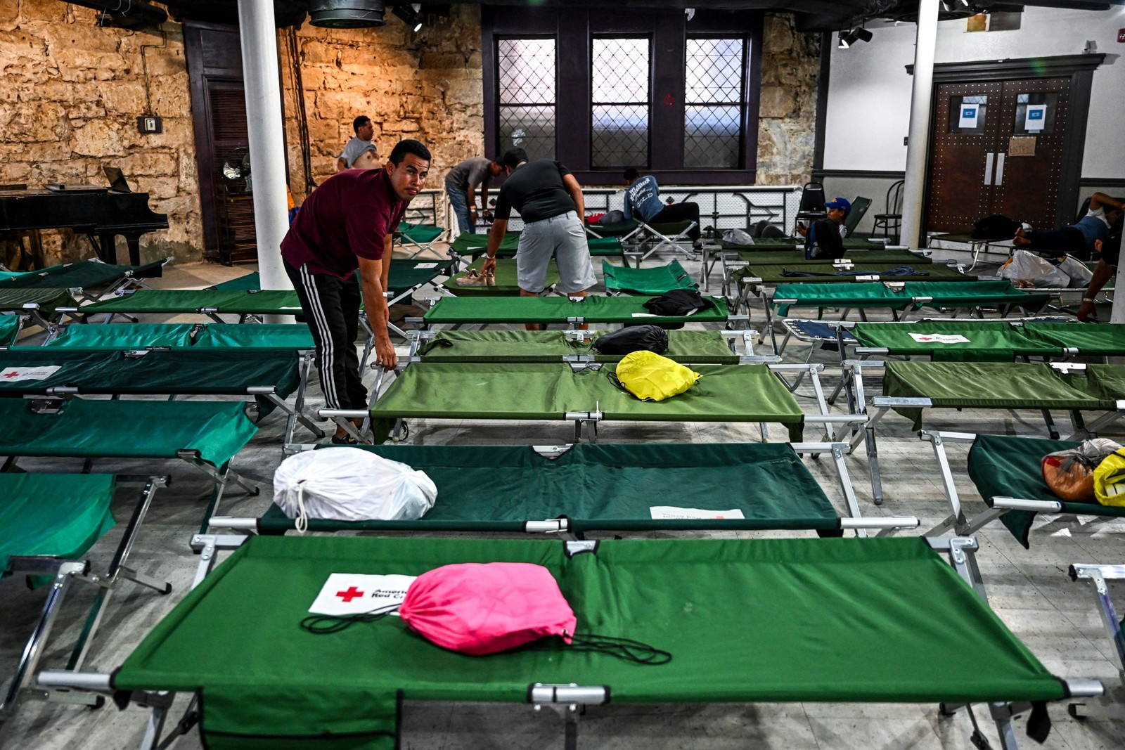 Migrantes montam suas camas dentro de abrigo em San Antonio. A instituição abre suas portas todos os dias das 19h às 8h e oferece jantar e cama para os imigrantes necessitados — Foto: CHANDAN KHANNA / AFP