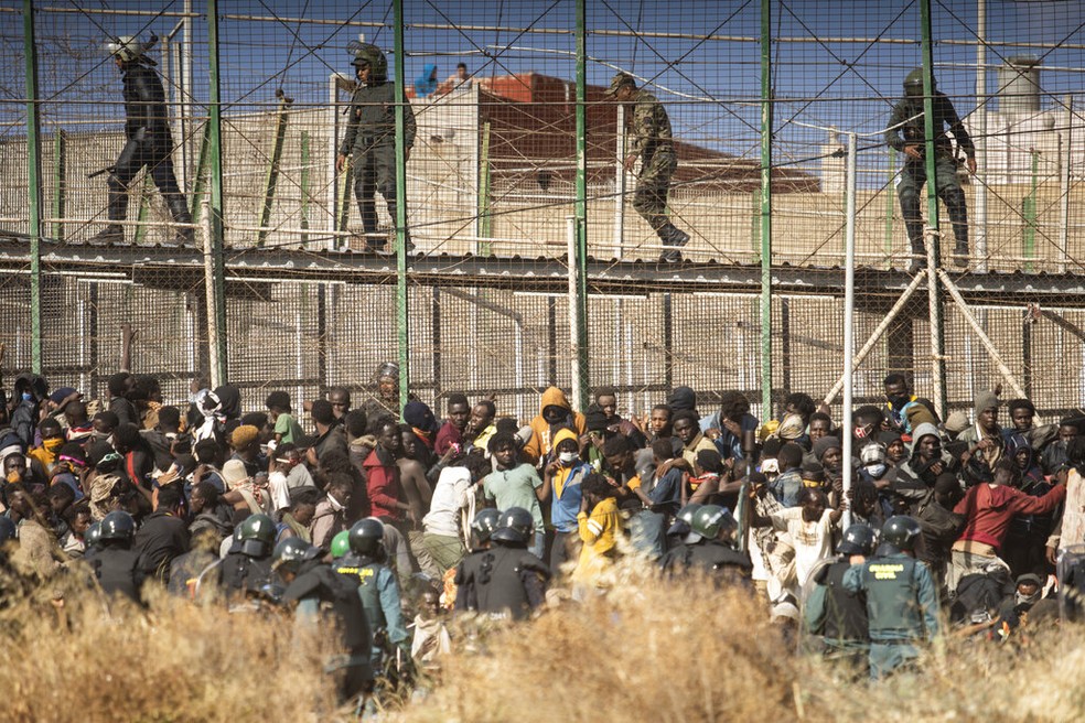Observado por policiais marroquinos, grupo de migrantes é cercado por homens da Guarda Civil espanhola após pulares cerca que divide o Marrocos de Melilla, cidade espanhola no norte da África, em 24 de junho de 2022. — Foto: Javier Bernardo/ Associated Press