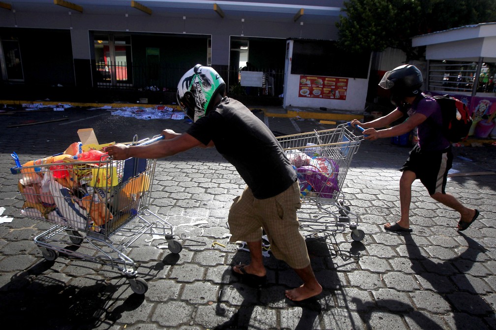 Pessoas com mercadorias saqueadas de uma loja empurram carrinhos de compras ao longo de uma rua depois de protestar contra uma reforma nos planos de pensão do Instituto Nacional de Seguro Social (INSS) em Managua, na Nicarágua (Foto: Jorge Cabrera/Reuters)