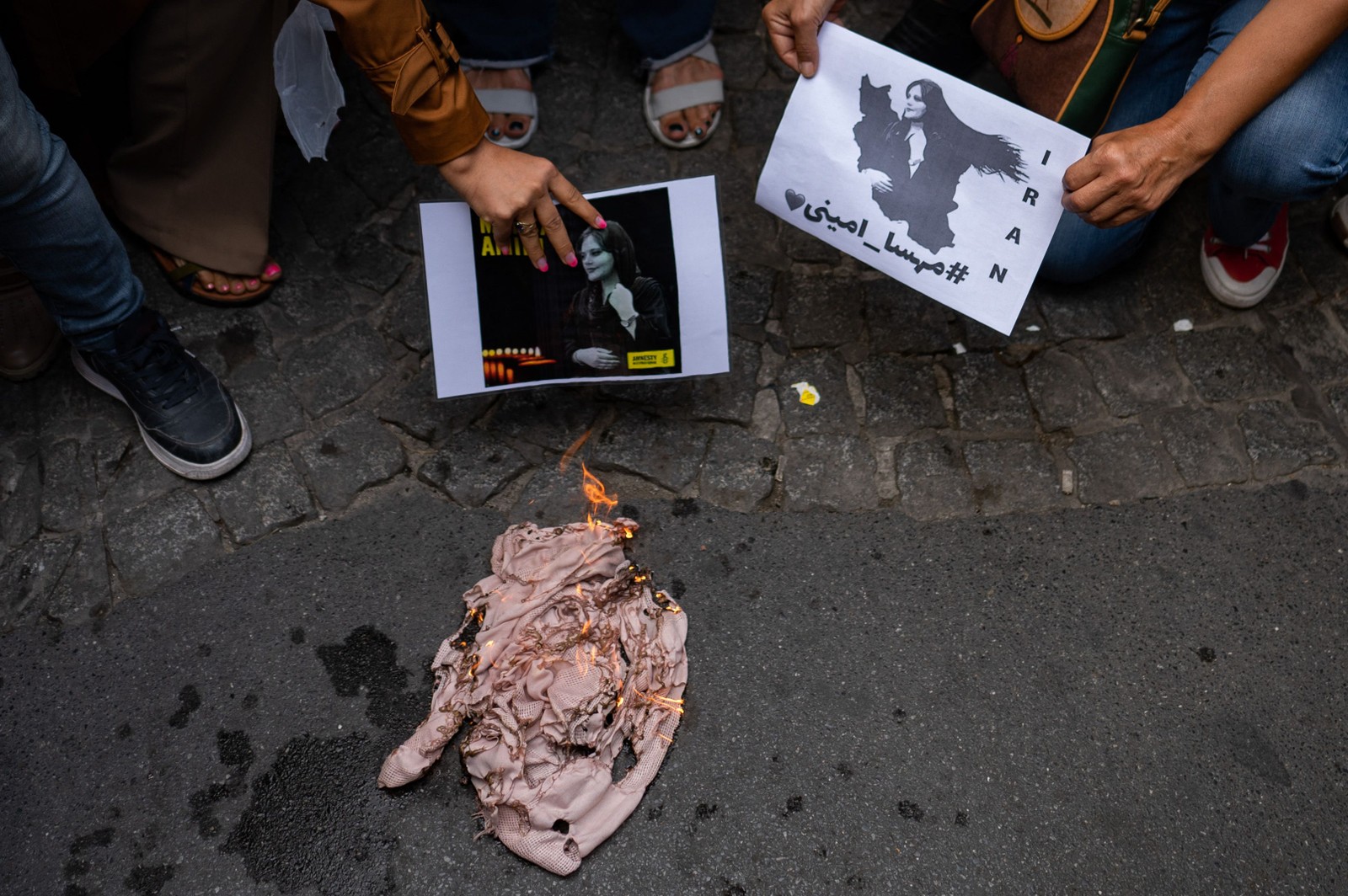 Mulher iraniana que vive na Turquia, queima seu hijab durante um protesto em frente ao consulado iraniano em Istambul — Foto: Yasin AKGUL / AFP