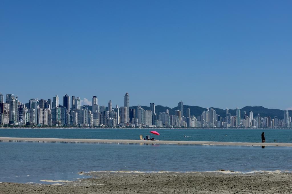 Banhistas nadam em meio a lixeiras em área com acúmulo de água na orla alargada em Balneário Camboriú; VÍDEO