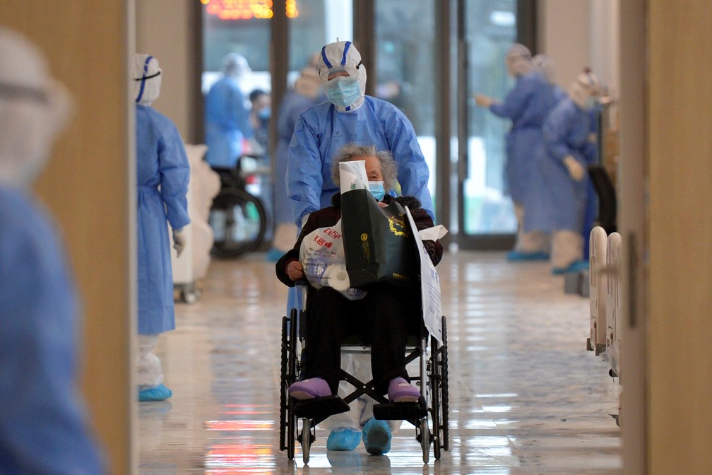 12 de fevereiro: Paciente com Covid-19, a doença provocada pelo novo coronavírus, é levado de cadeira de rodas no hospital de Wuhan, na China, cidade epicentro da doença. — Foto: China Daily via Reuters