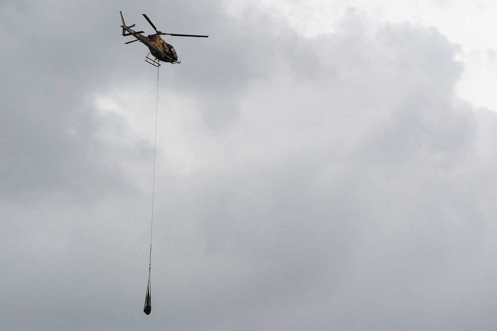 Um helicÃ³ptero leva embora um corpo retirado da lama, depois do rompimento da barragem da Vale em Brumadinho. â€” Foto: Leo Correa/AP