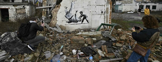 Ucranianos tiram foto de grafite 'estilo Banksy' que retrata uma criança derrubando um adulto com golpe de judô — Foto: Genya SAVILOV / AFP