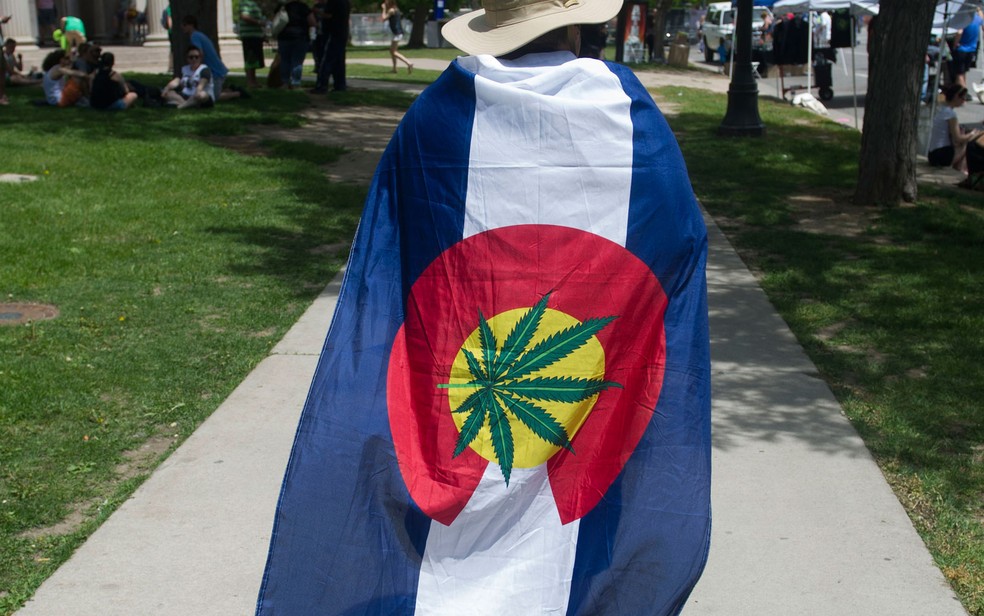 Homem carrega bandeira do estado de Colorado com desenho de folha de maconha em Denver, em foto de 20 de maio de 2016 — Foto: Jason Connolly/AFP