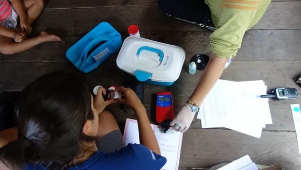 A pesquisadora Patrícia Torres coleta uma amostra de sangue de uma das crianças entre 6 meses e 5 anos analisadas no estudo, no Amazonas (Foto: LUKE PARRY/ DIVULGAÇÃO via BBC)