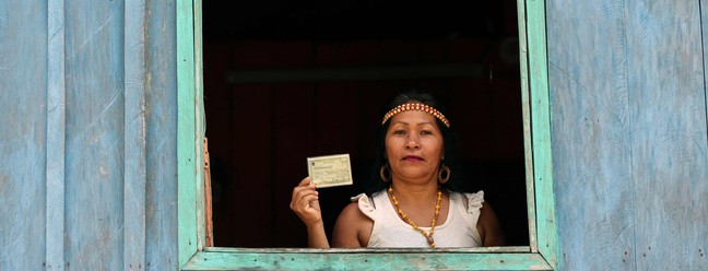 Indígena Kambeba posa com título de eleitor, na Comunidade Três Unidos, no rio Negro, Amazonas — Foto: MICHAEL DANTAS/AFP