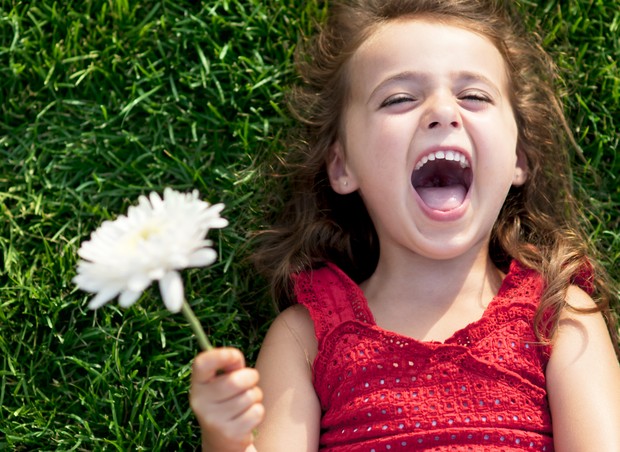 menina; grama; sorriso; flor; feliz; felicidade (Foto: Thinkstock)