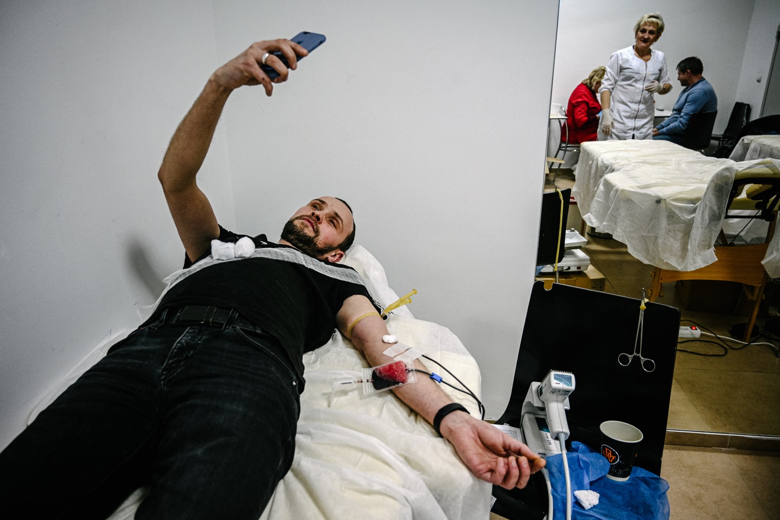 Um homem tira uma selfie enquanto doa sangue para os militares, como parte do evento de caridade "Torne-se um doador de sangue - Confesse seu amor pelo exército ucraniano", na cidade ucraniana ocidental de Lviv.  — Foto: YURIY DYACHYSHYN / AFP - 14/02/2023