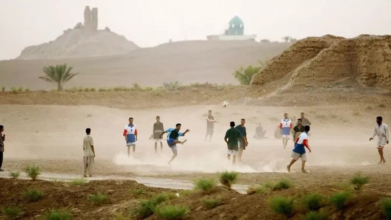 Jovens iraquianos jogam futebol à sombra das ruínas de um zigurate em Borsippa, no Iraque (Foto: MARIO TAMA/GETTY IMAGES via BBC)